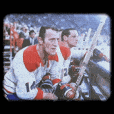 two hockey players wearing victoria gloves sit in the stands
