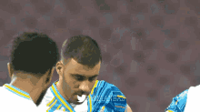 a man in a blue and yellow jersey talks to another man in a white shirt