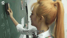 a woman with blonde hair is writing on a blackboard with a twice logo