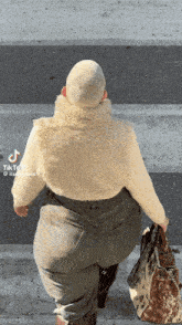 a woman with a shaved head is walking down the street with a purse in her hand