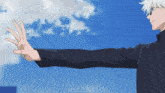 a person 's arm is extended in front of a cloudy blue sky