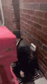 a man is kneeling down in front of a brick wall with a red box that says ' coca cola ' on it