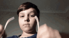 a young boy in a blue shirt is holding a piece of paper in his hands