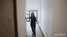 a woman in a black shirt is walking down a hallway in an empty apartment .