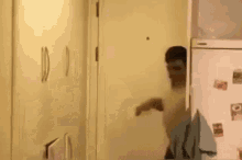 a man with a mask on his face is standing in front of a refrigerator in a hallway .