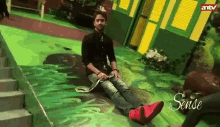 a man is sitting on a green floor with a snake around his neck .