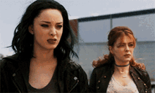 two women standing next to each other with one having green hair