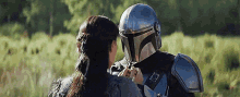 a woman is standing next to a man in a helmet in a field .