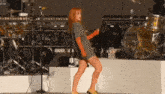 a woman is dancing on a stage with a drum set in the background that says ' drums ' on it