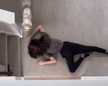 a woman crawls on the floor next to a dog