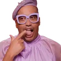 a man wearing glasses and a purple shirt is pointing at his tongue