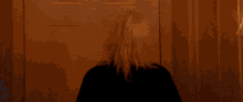 a woman in a black shirt is standing in a dark hallway with a lamp