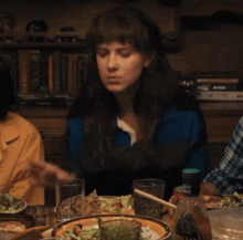 a woman sitting at a table with plates of food and a napkin