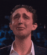 a man in a suit and white shirt is making a sad face