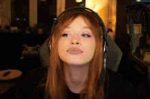 a woman with red hair is wearing headphones and looking at the camera
