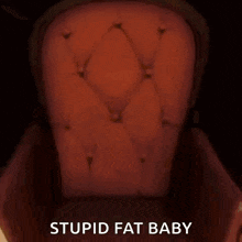a boy is sitting in a red chair with the words `` stupid fat baby '' .