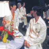 two men are sitting at a table with a plate of food on it