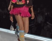 a woman in a pink skirt is walking down the runway at a fashion show