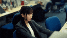 a woman in a suit sits at a desk with her mouth open