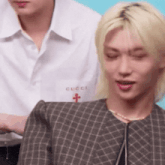 a man with blonde hair is wearing a plaid jacket with the word gucci embroidered on it