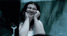 a woman is laughing with her hands on her face in front of a mirror .