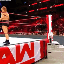 a woman is standing in a wrestling ring with a banner that says raw on it .