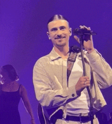 a man is singing into a microphone while a woman stands behind him .