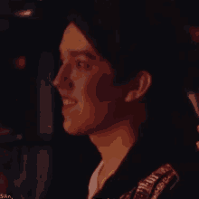 a close up of a man 's face in a dark room with a smile on his face .