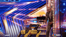 a man is standing next to a robot on a stage that says nbc on the bottom
