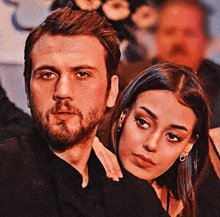 a man and a woman are sitting next to each other and the woman is looking at the camera .