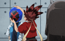 a boy in a red shirt holds a blue helmet with a red x on it