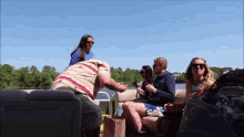 a group of people are sitting on a boat and one of them is wearing sunglasses