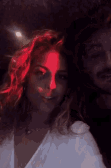 a man and a woman are posing for a picture with a red light projected on their faces