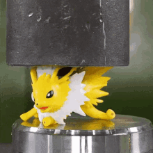 a yellow and white pokemon figurine is sitting on top of a metal surface .
