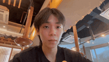 a young man in a black shirt looks at the camera in a restaurant