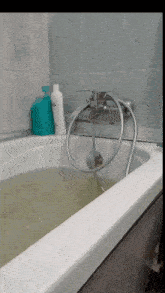 a bathtub filled with green water and a shampoo bottle on the side