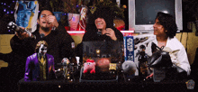 three men are sitting at a table with toys and a box that says star wars on it