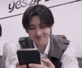 a young man is holding a cell phone and smiling .