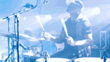 a man playing drums in front of a microphone with a blue background