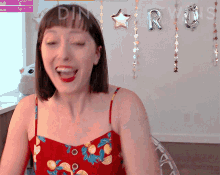 a woman in a red floral dress is laughing in front of a sign that says " follow "