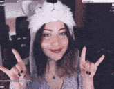 a woman wearing a wolf hat is making a peace sign with her hands