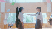 a girl holding a guitar case talks to another girl in a school hallway