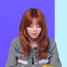 a woman with red hair wearing a denim jacket