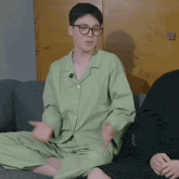 a man in a green pajama set sits on a couch