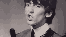 a black and white photo of a man singing into a microphone .