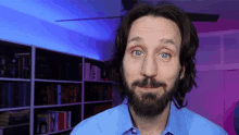 a man with a beard wearing a blue shirt is looking at the camera