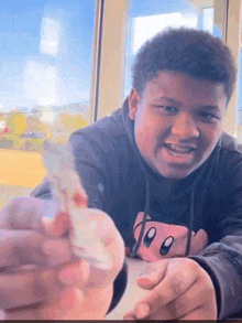 a young man wearing a kirby hoodie is holding something in his hands