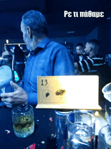 a man is sitting at a table with a sign that says 13 on it