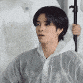a young man wearing a white plastic raincoat looks at the camera