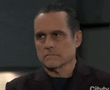 a man in a suit is looking at the camera with a serious expression on his face .